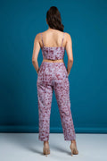 Woman wearing a purple tie dye top and pants set against a blue background