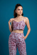 Woman wearing a matching purple tie-dye top and pants against a blue background