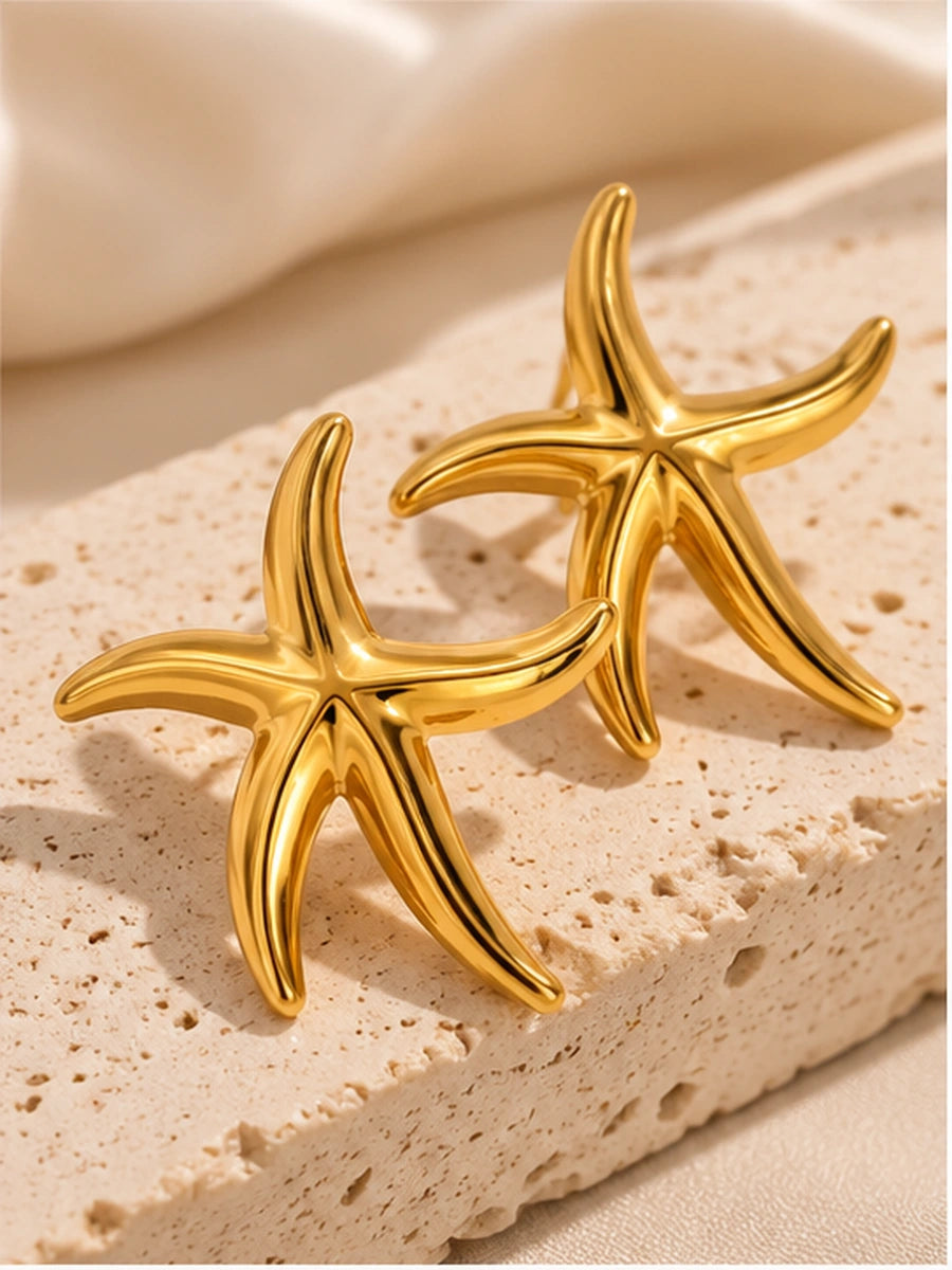 Gold starfish statement earrings photographed as a pair on stone with soft shadows