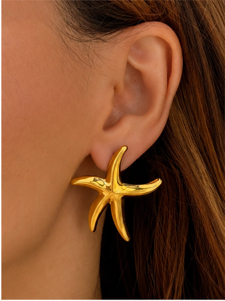 Gold starfish statement earrings photographed as a pair on stone with soft shadows