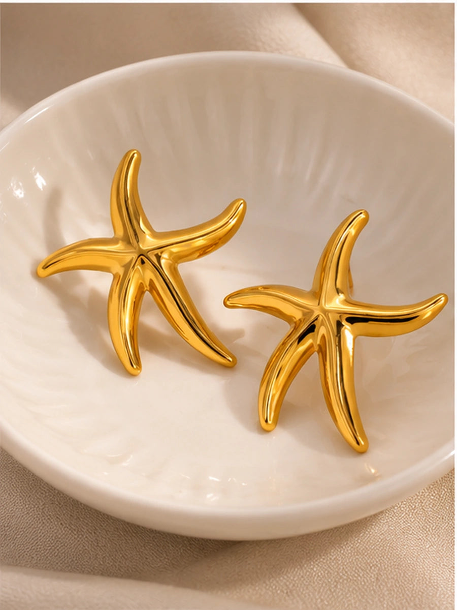 Pair of gold starfish earrings in cream ceramic dish