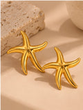 Gold starfish earrings pair on warm neutral studio background