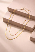 Gold necklace with small beads on a beige surface