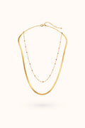 Gold necklace with small beads on a white background