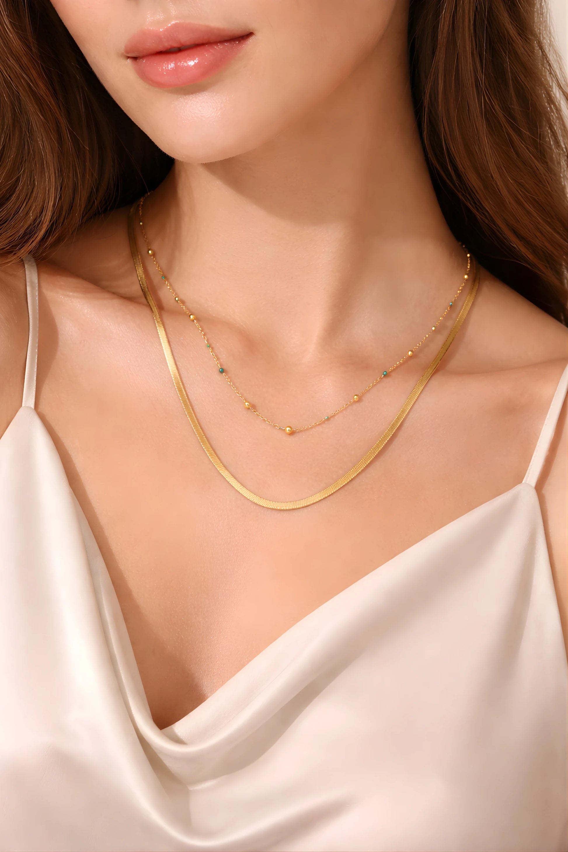 Close-up of a woman wearing a gold necklace with a white top.